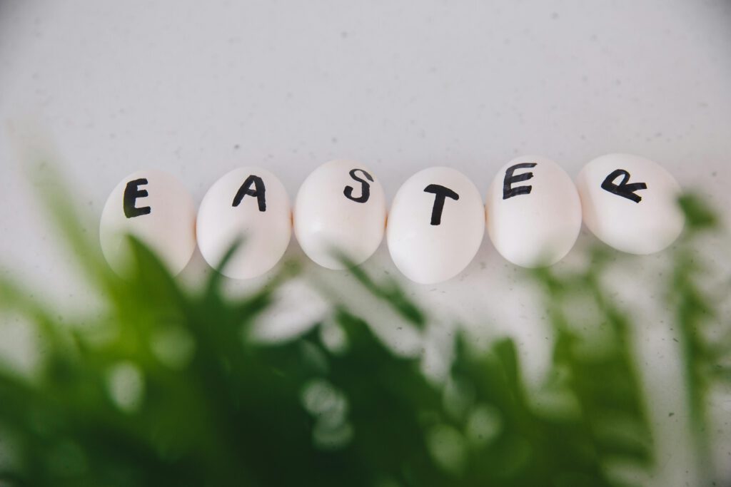 White eggs labeled with 'EASTER' surrounded by greenery for festive decor.